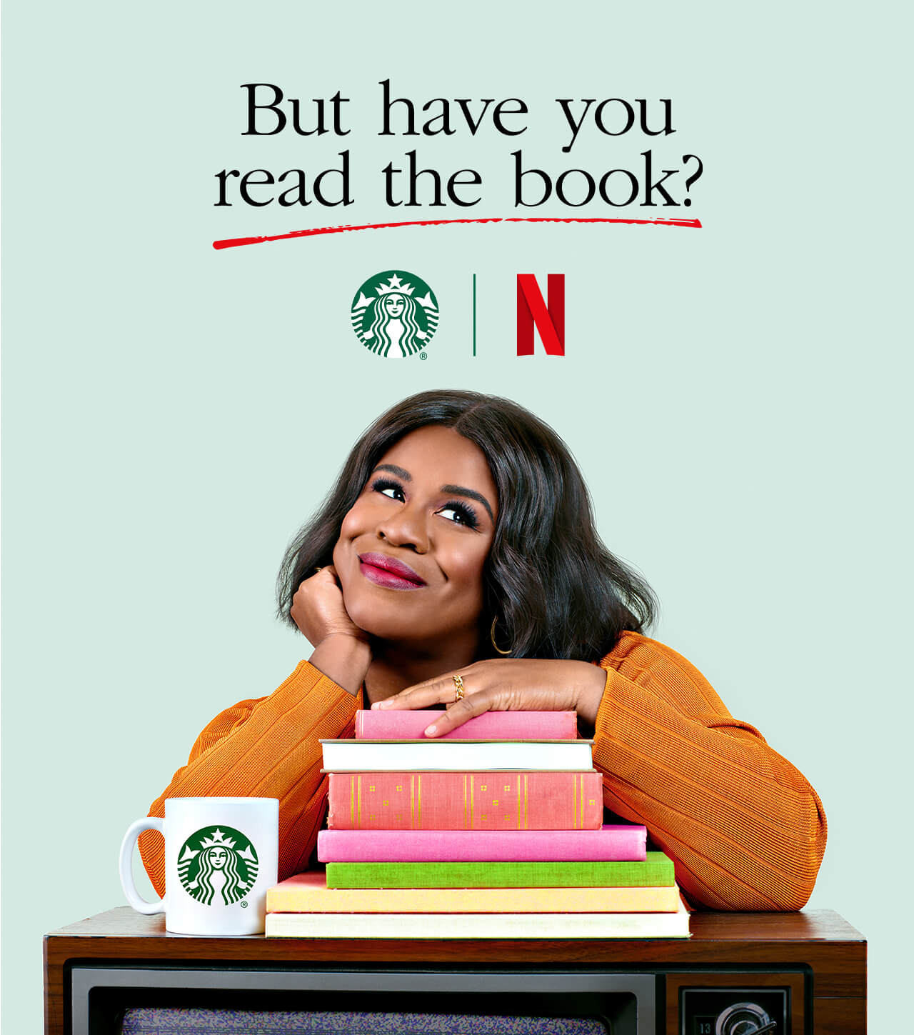 Actress Uzo Aduba poses with a pile of books, a TV and a Starbucks mug to promote a new social series named But Have You Read the Book.