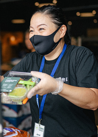 Woman handing out food at a food bank.