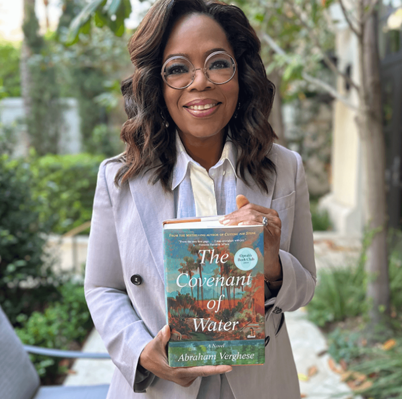 Woman smiling while holding a book titled "The Covenant of Water."