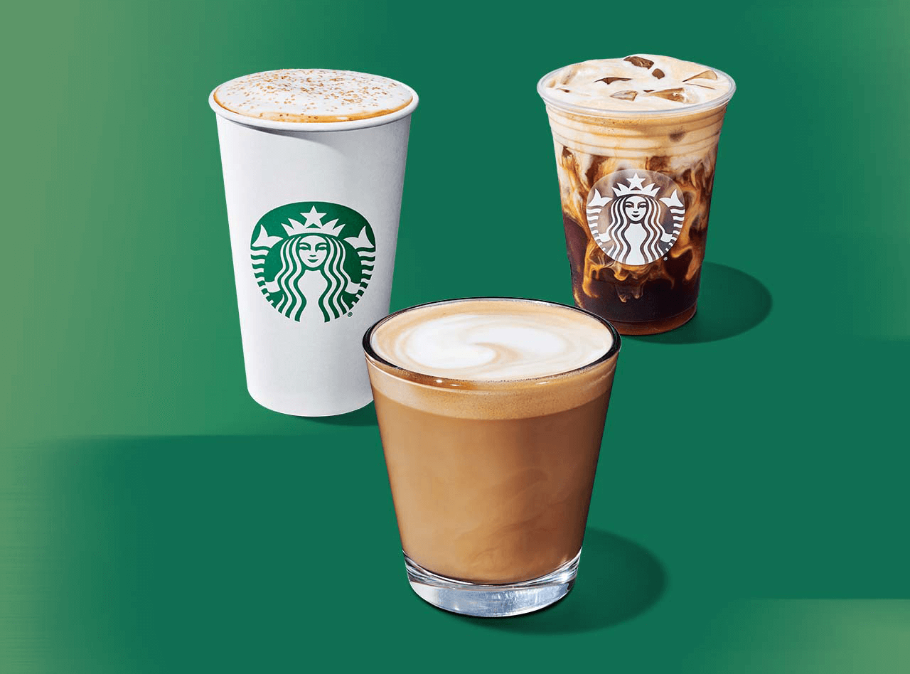 Trois boissons hivernales de Starbucks : l'une dans un gobelet blanc, une autre dans un gobelet pour boisson froide transparent et la dernière dans une tasse en verre de format Piccolo avec une crema onctueuse, le tout sur un fond vert apaisant.