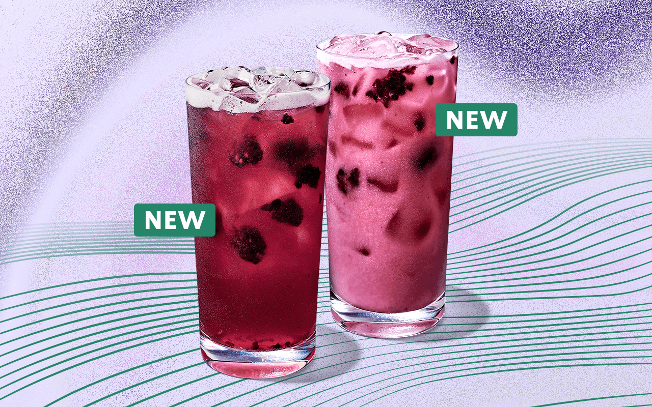 Two Starbucks Refresher beverages in glassware on a pale purple background with radiating green lines. One of drinks is a translucent purple colour with blackberry inclusions and ice visible and the second is lighter purple and more opaque. Each beverage has a small green sticker indicating it is new.