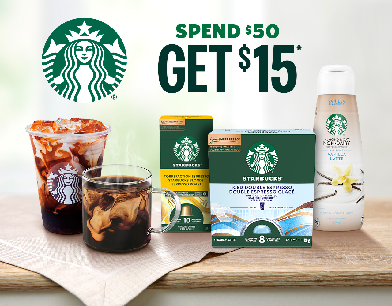 A Starbucks café cup sits next to a glass cup beside Coffee At Home products on a kitchen counter. Text reads, “Spend $50 Get $15.”