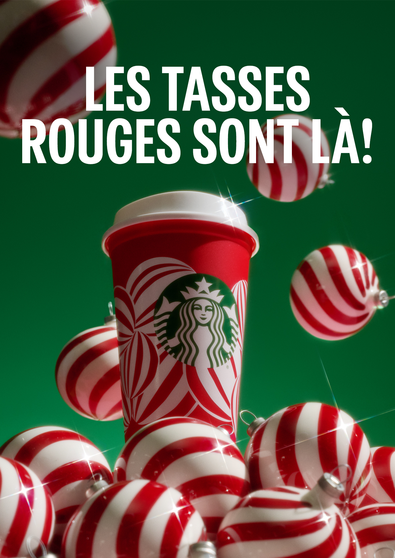 LES TASSES ROUGES SONT LÀ! | Une tasse rouge réutilisable Starbucks sur une pile de décorations rouges et blanches.