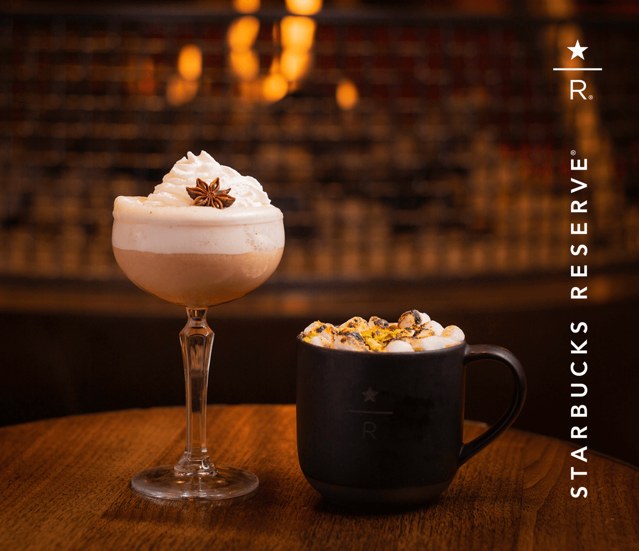 A whipped cream-topped coupe of Maharaja Chai Nog next to a foamy mug of Pistachio Buttered Rum.
