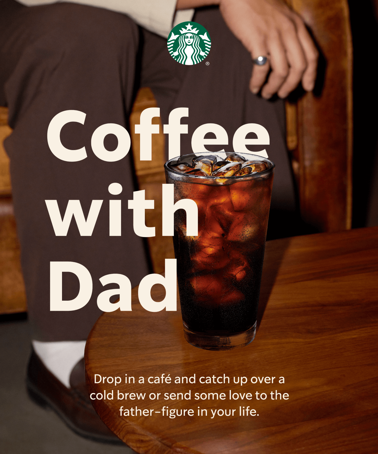 STARBUCKS® | A photograph of a man sitting in Starbucks café. In front of him is a cold brew with ice on a table. | Coffee with Dad | Drop in a café and catch up over a cold brew or send some love to the father-figure in your life.
