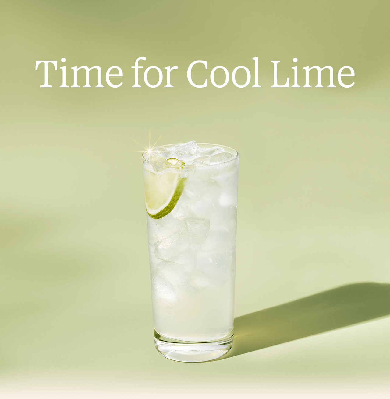 Time for Cool Lime | A soft, hazy green looking iced beverage captures the light of its pale green background. Suspended among the ice is a lime slice