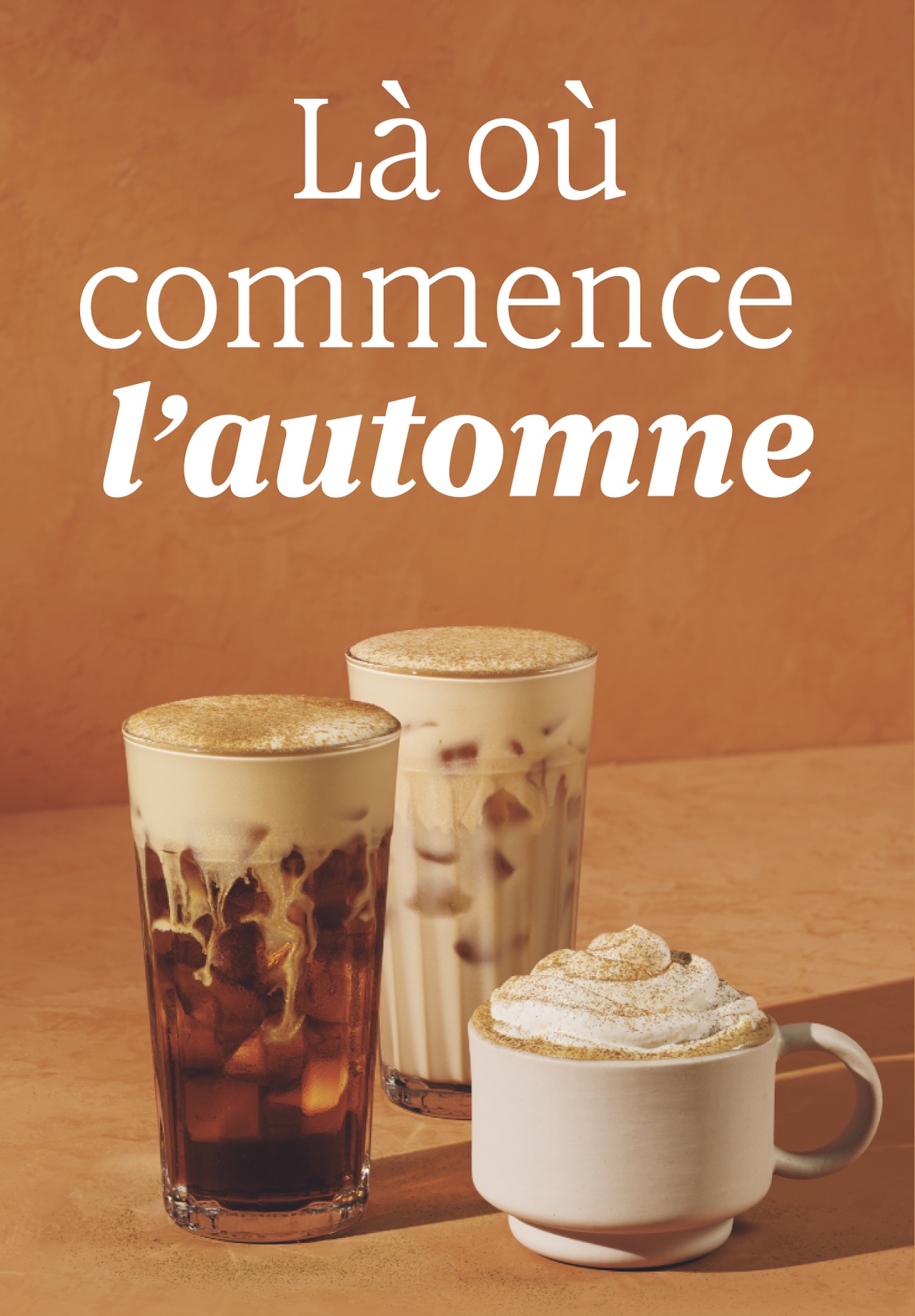 Là où commence l’automne | Trois boissons automnales sont montrées sur un fond orange chaud. À gauche, dans un verre transparent, le café infusé à froid avec crème à la citrouille, garni d'une mousse pâle et montrant des tourbillons de lait blanc crémeux. Au centre, le riche et crémeux chai glacé avec crème à la citrouille, de couleur beige, recouvert d'une appétissante mousse et saupoudré d'épices pour tarte à la citrouille. À droite, dans une tasse blanche, le Latte à la citrouille épicée, garni d'une attrayante crème fouettée saupoudrée d'épices pour tarte à la citrouille.